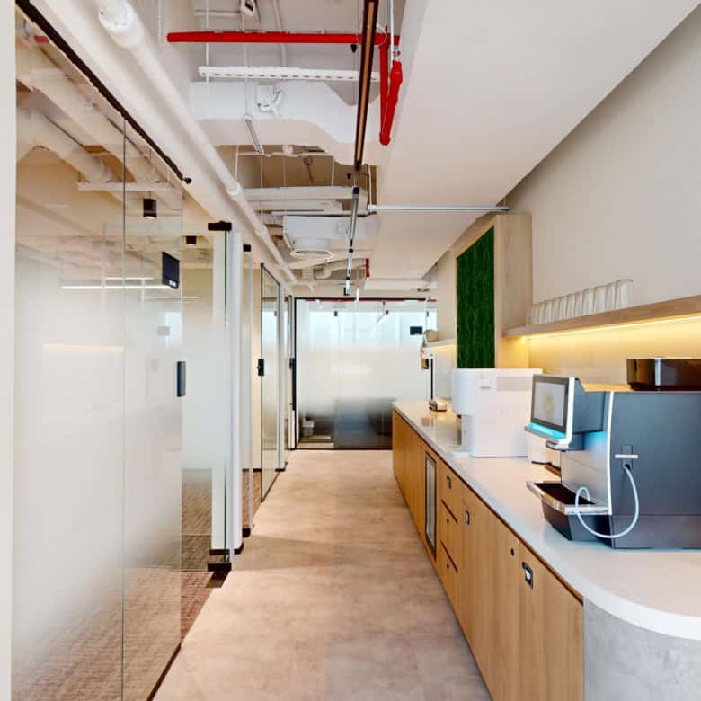 A sleek, well-lit office lounge with coffee machines, glass dividers, and modern decor, perfect for entrepreneurs and professionals in UAE.