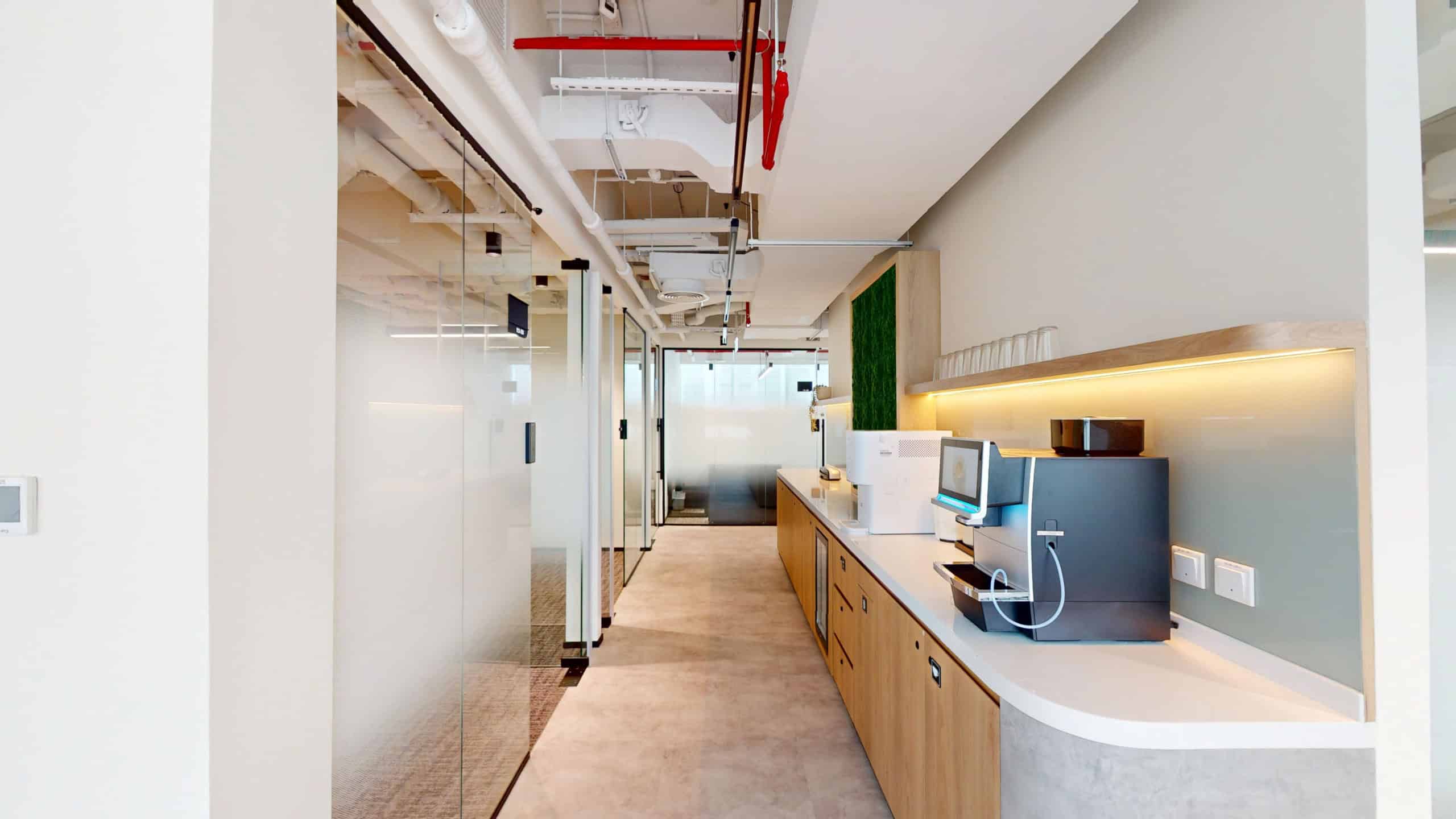 A sleek, well-lit office lounge with coffee machines, glass dividers, and modern decor, perfect for entrepreneurs and professionals in UAE.