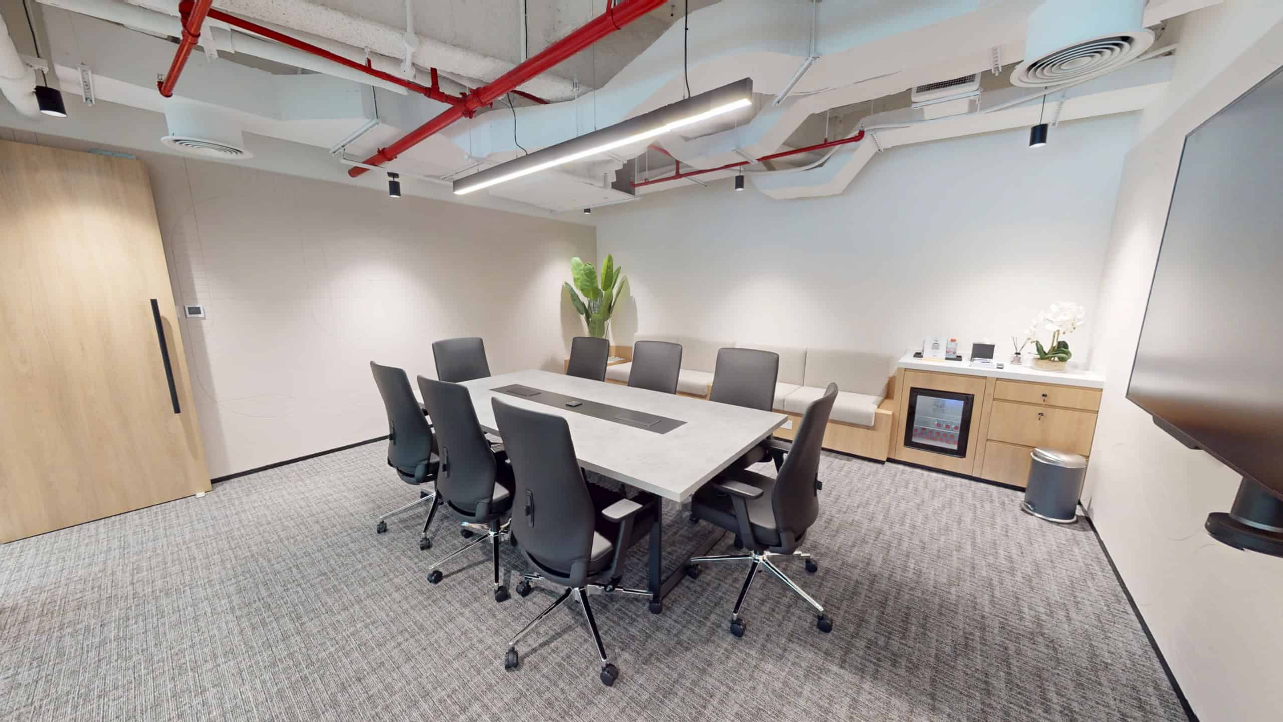 Bright, minimalist coworking meeting room featuring a large table, comfortable chairs, and tech-enabled workstations in Dubai.