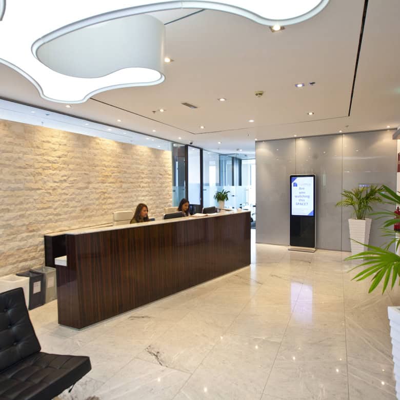 Bright, contemporary office reception in Dubai with stylish decor, plants, and digital signage for client arrivals.