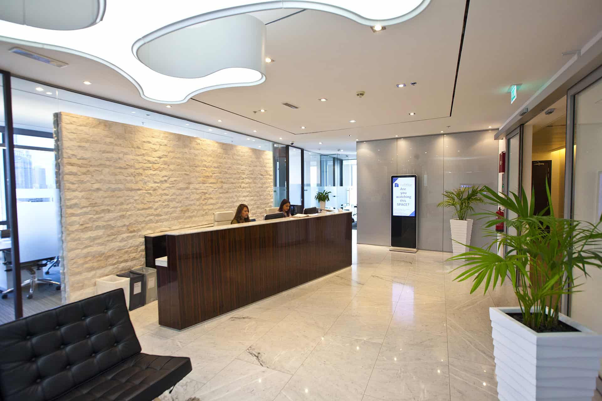 Bright, contemporary office reception in Dubai with stylish decor, plants, and digital signage for client arrivals.
