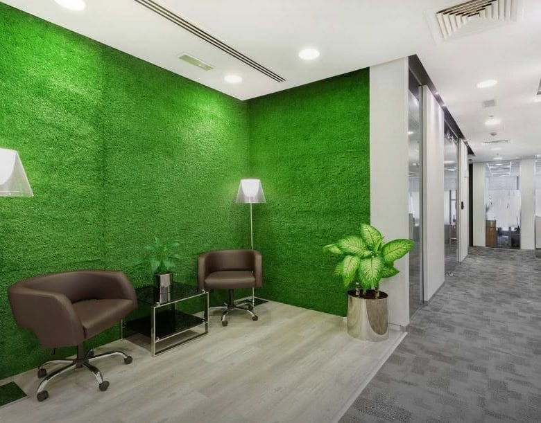 Modern coworking space with vibrant green wall, comfortable seating, and collaboration areas in Dubai.