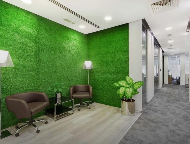 Modern coworking space with vibrant green wall, comfortable seating, and collaboration areas in Dubai.