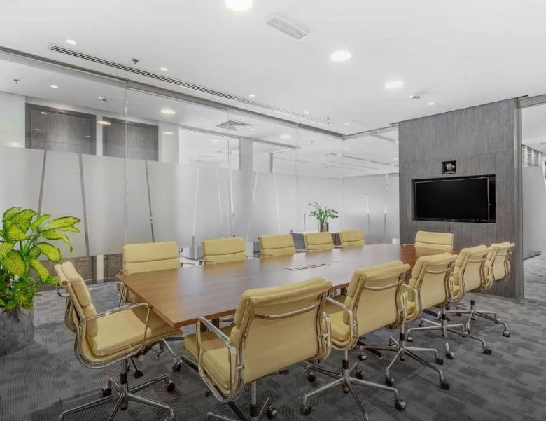 Spacious conference room with glass walls, comfortable chairs, and a large TV screen for meetings and collaborations.