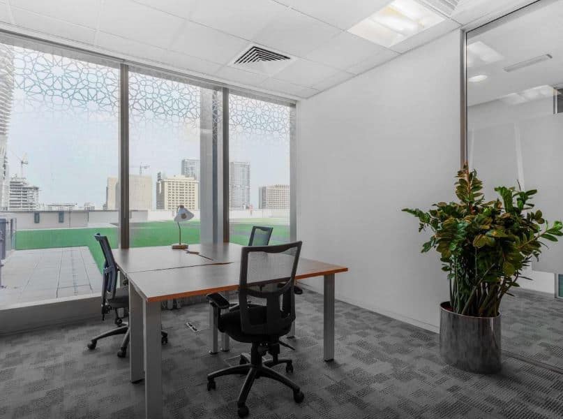 UAE coworking office with large windows, modern desk setup, and city skyline views.