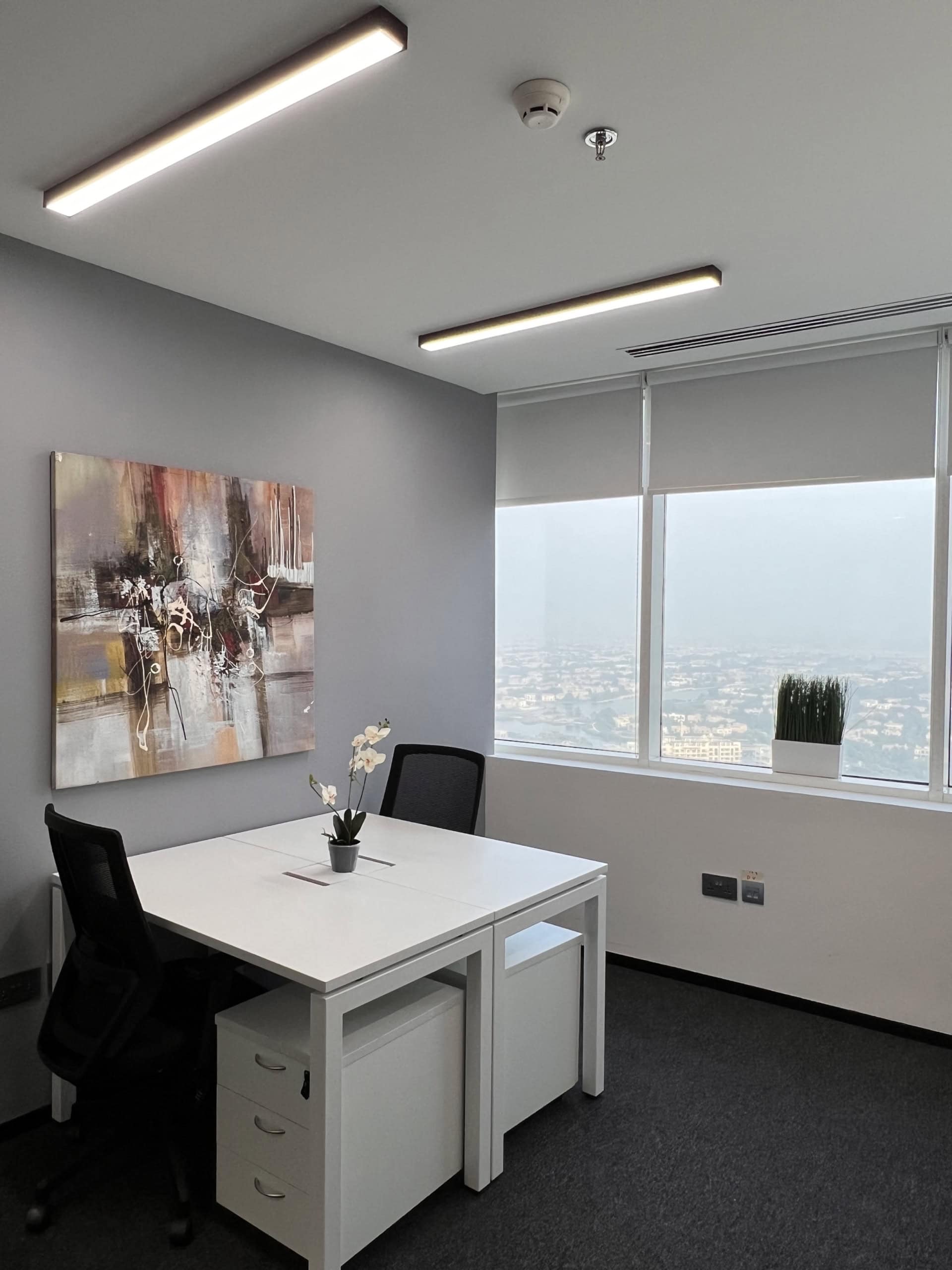 Bright office with large windows, minimalist decor, and abstract art for productivity.
