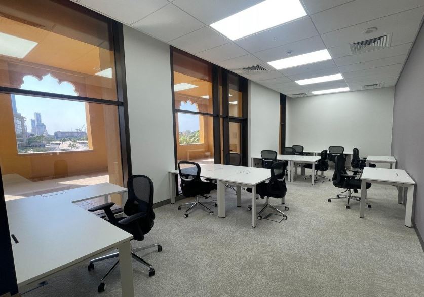 Bright Dubai coworking space with large windows, shared desks, and professional work environment.