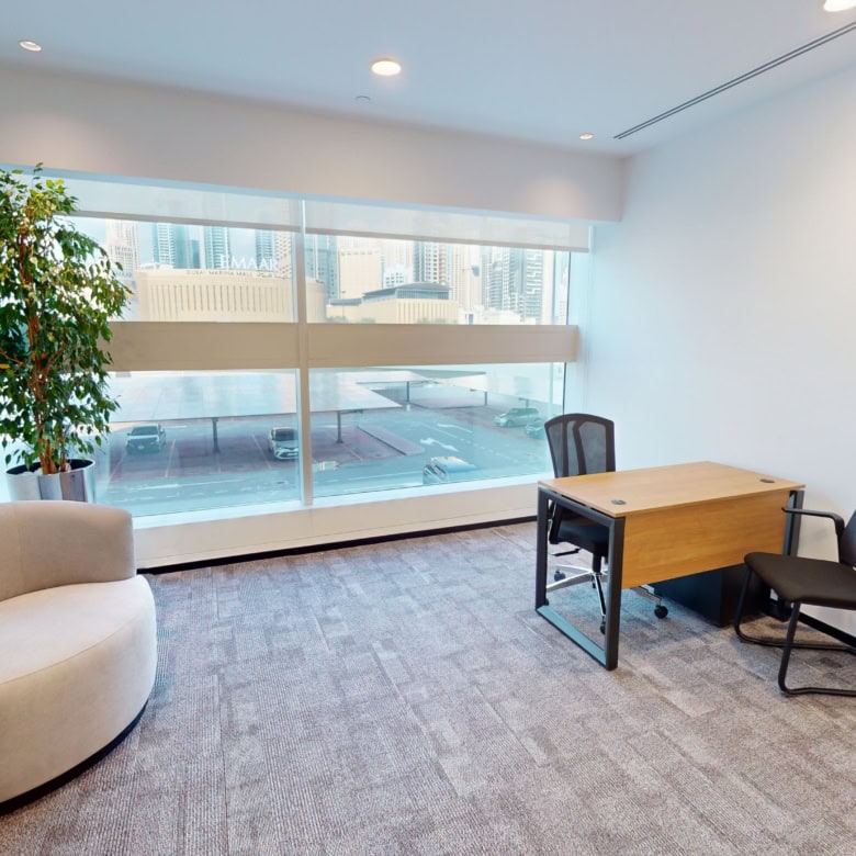 Bright office space with large windows, ergonomic chairs, and indoor plants in Dubai.