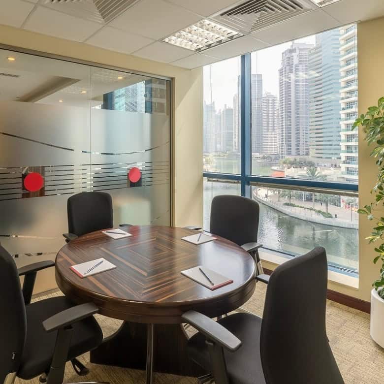 A professional conference room at Nextspace UAE featuring floor-to-ceiling windows, cityscape views, and contemporary office furniture.