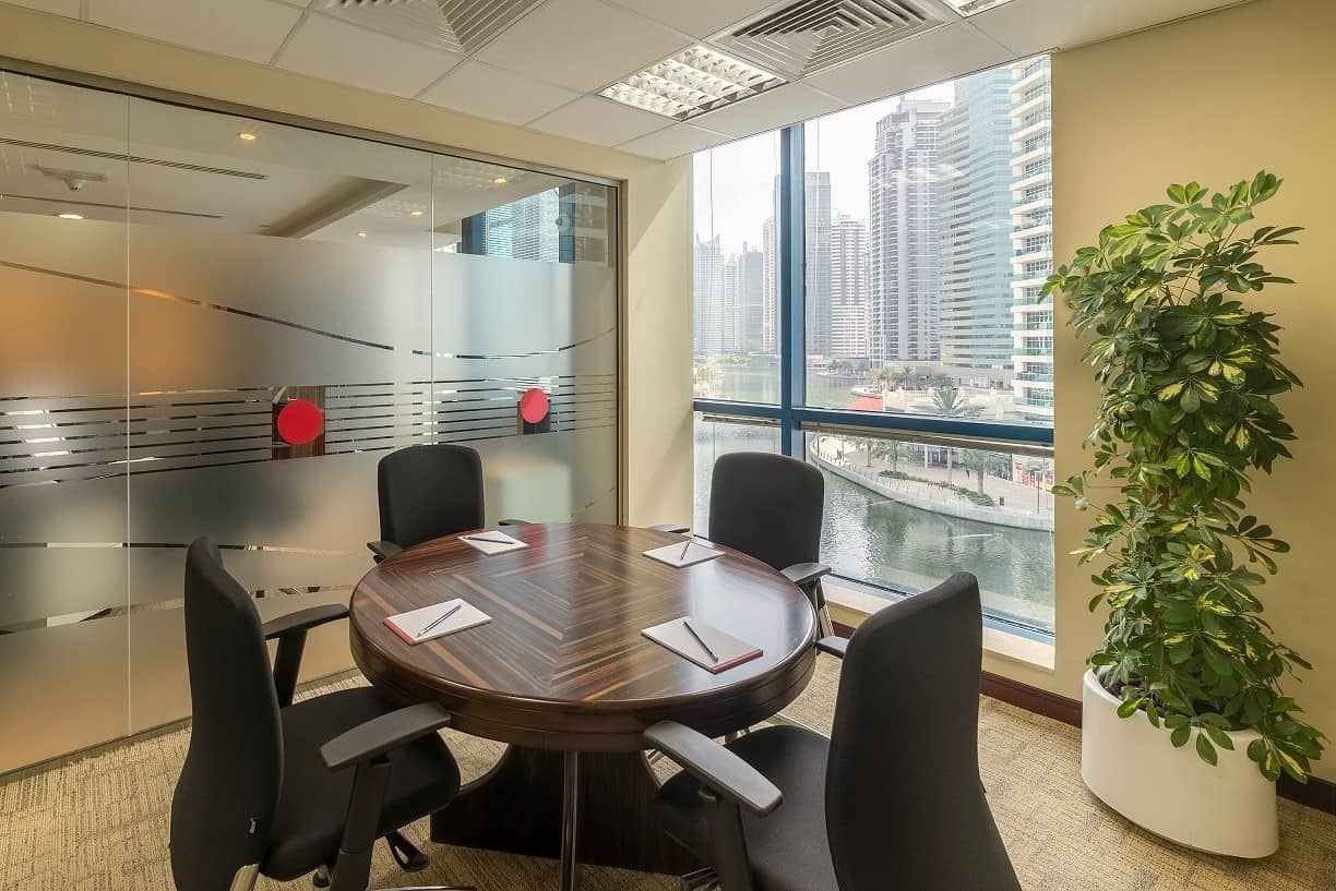 A professional conference room at Nextspace UAE featuring floor-to-ceiling windows, cityscape views, and contemporary office furniture.