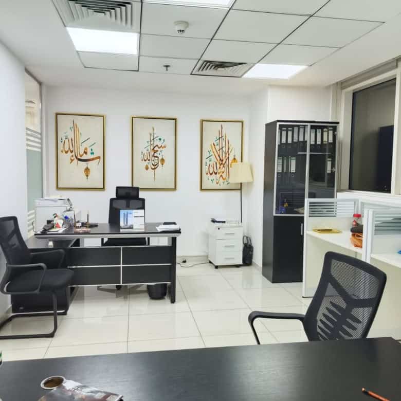 Spacious Dubai coworking space featuring desks, chairs, and Islamic artwork for professional work environment.