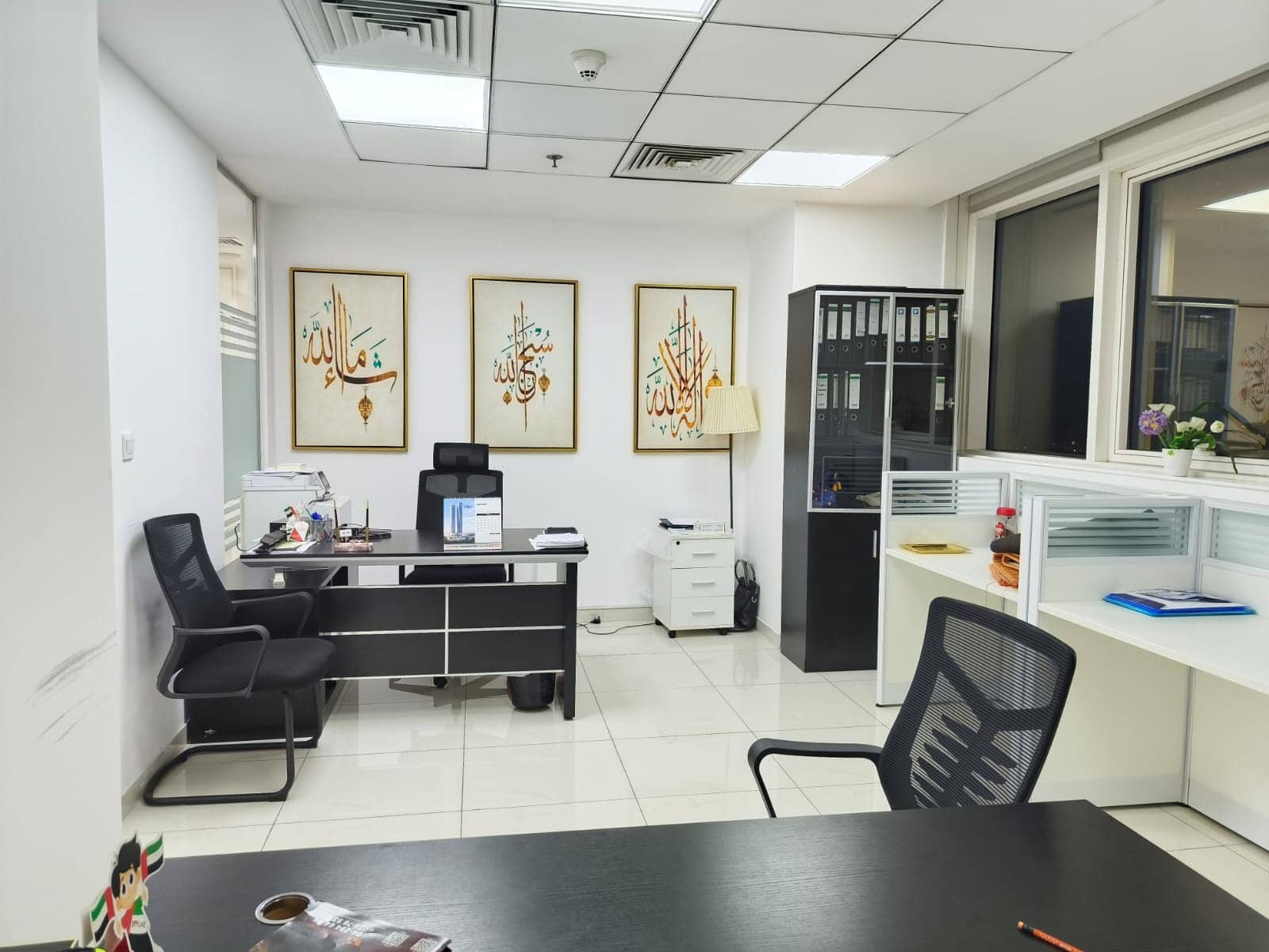 Spacious Dubai coworking space featuring desks, chairs, and Islamic artwork for professional work environment.