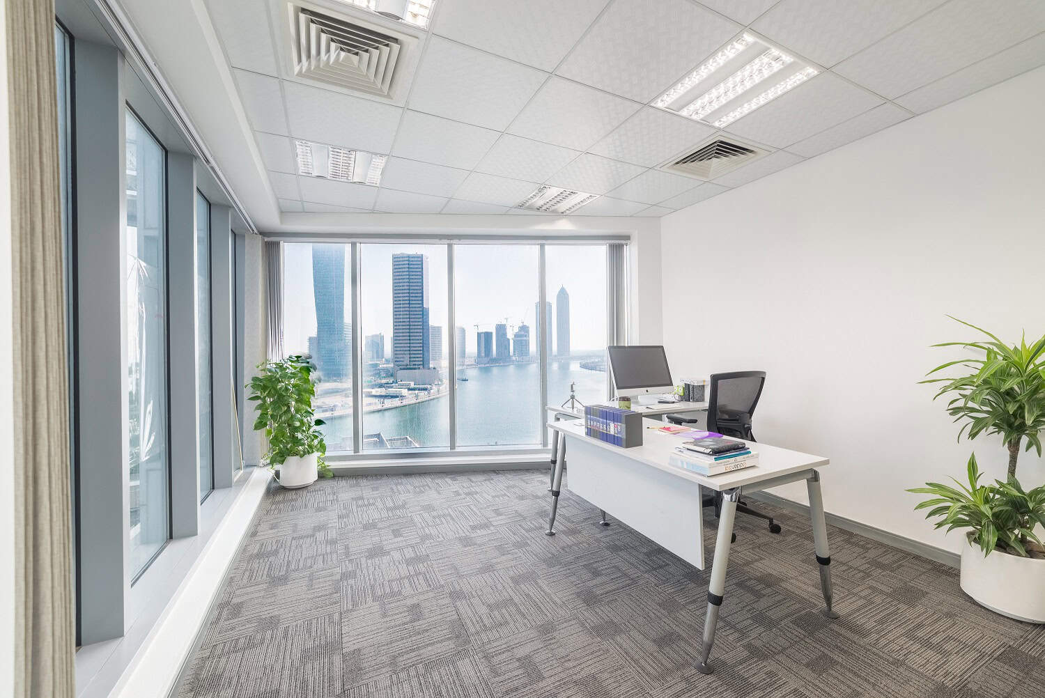 Bright office with large windows overlooking Dubai's skyline and water, ideal for productivity and business growth.