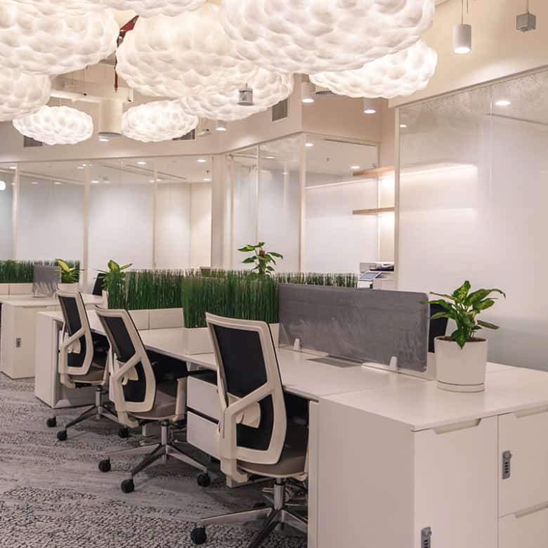 Bright coworking workspace featuring cloud-shaped ceiling lights and ergonomic desks in Dubai.