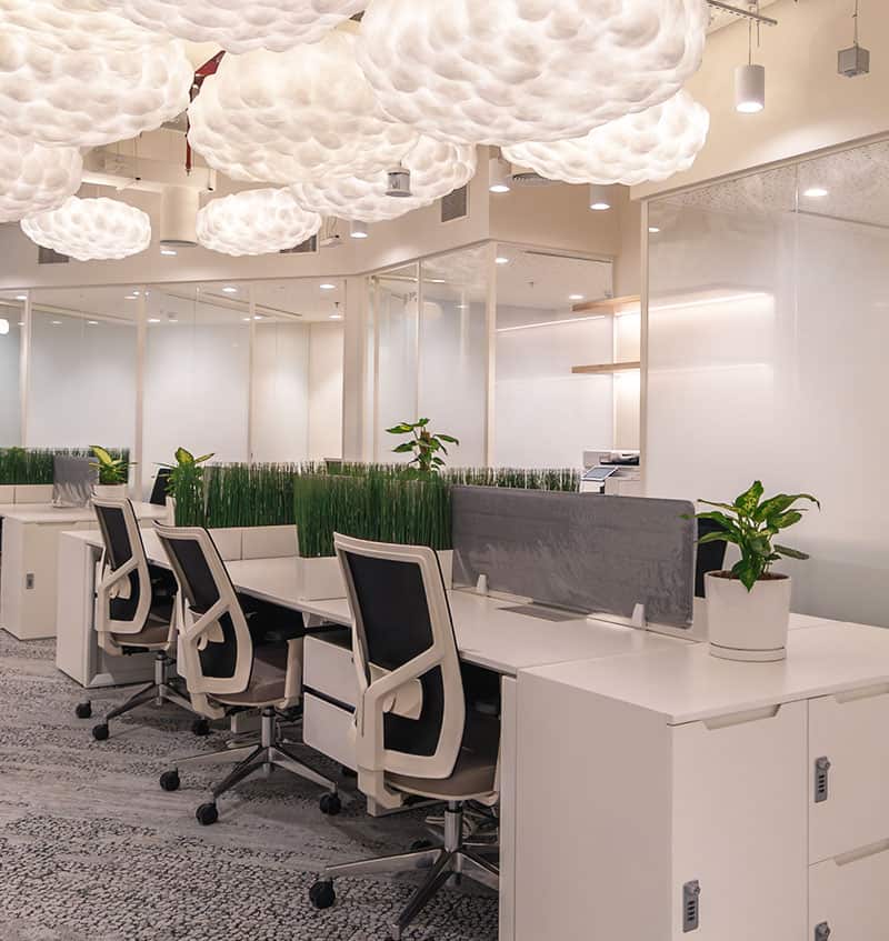 Bright coworking workspace featuring cloud-shaped ceiling lights and ergonomic desks in Dubai.
