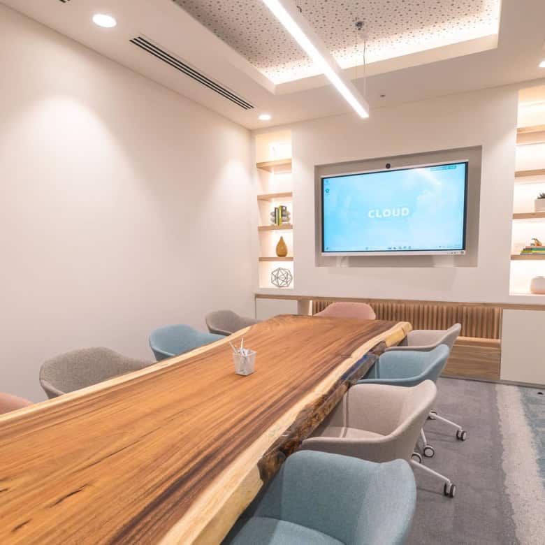 Stylish coworking space meeting room with wooden table and colorful chairs in Dubai, ideal for business meetings and collaborative work.