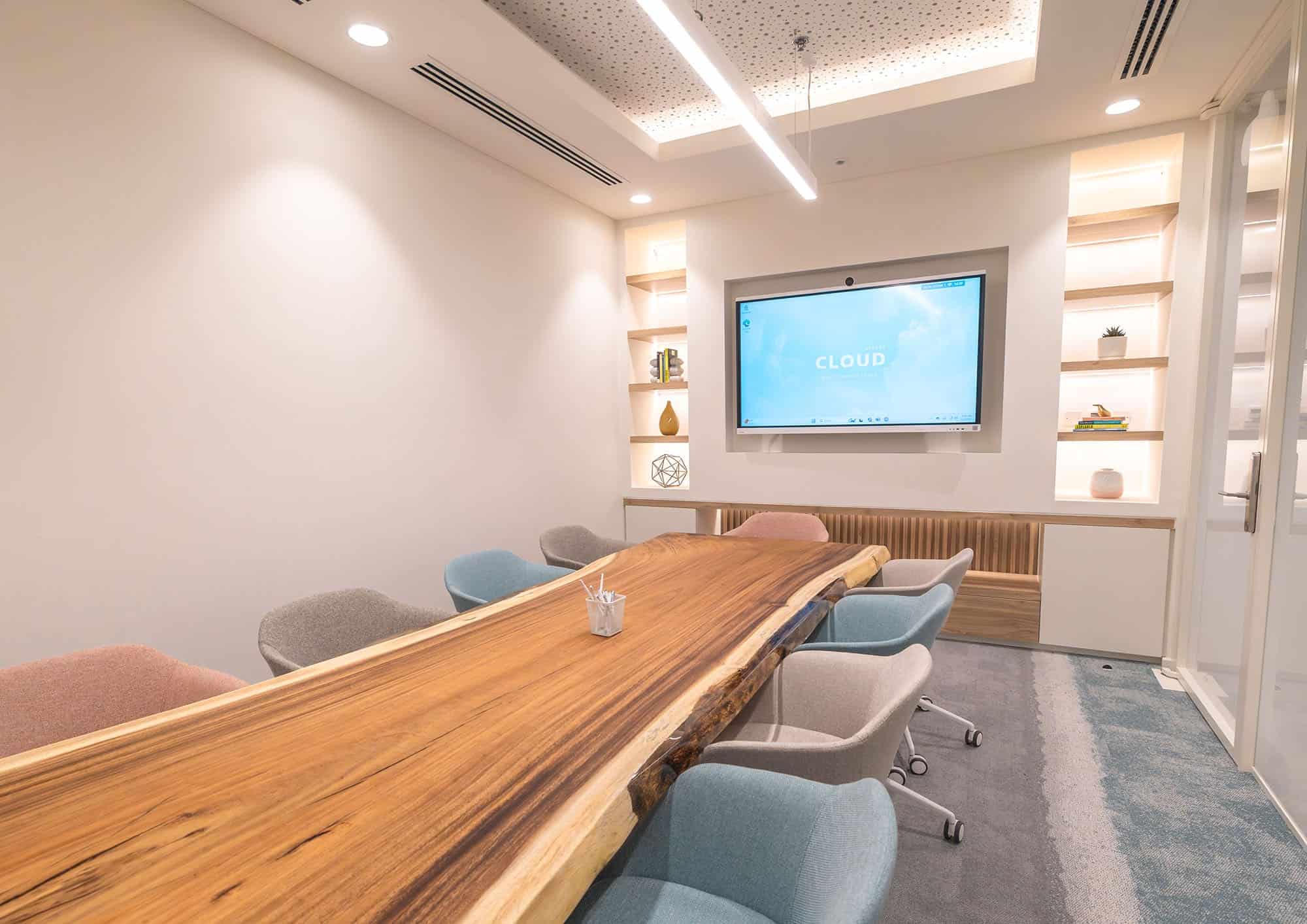 Stylish coworking space meeting room with wooden table and colorful chairs in Dubai, ideal for business meetings and collaborative work.