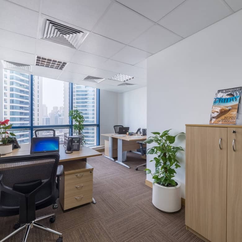 Bright office workspace in Dubai with large windows and coworking desks.