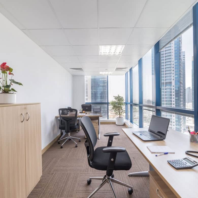 Modern office with large windows and coworking desks in Dubai, UAE, promoting productivity and business growth.