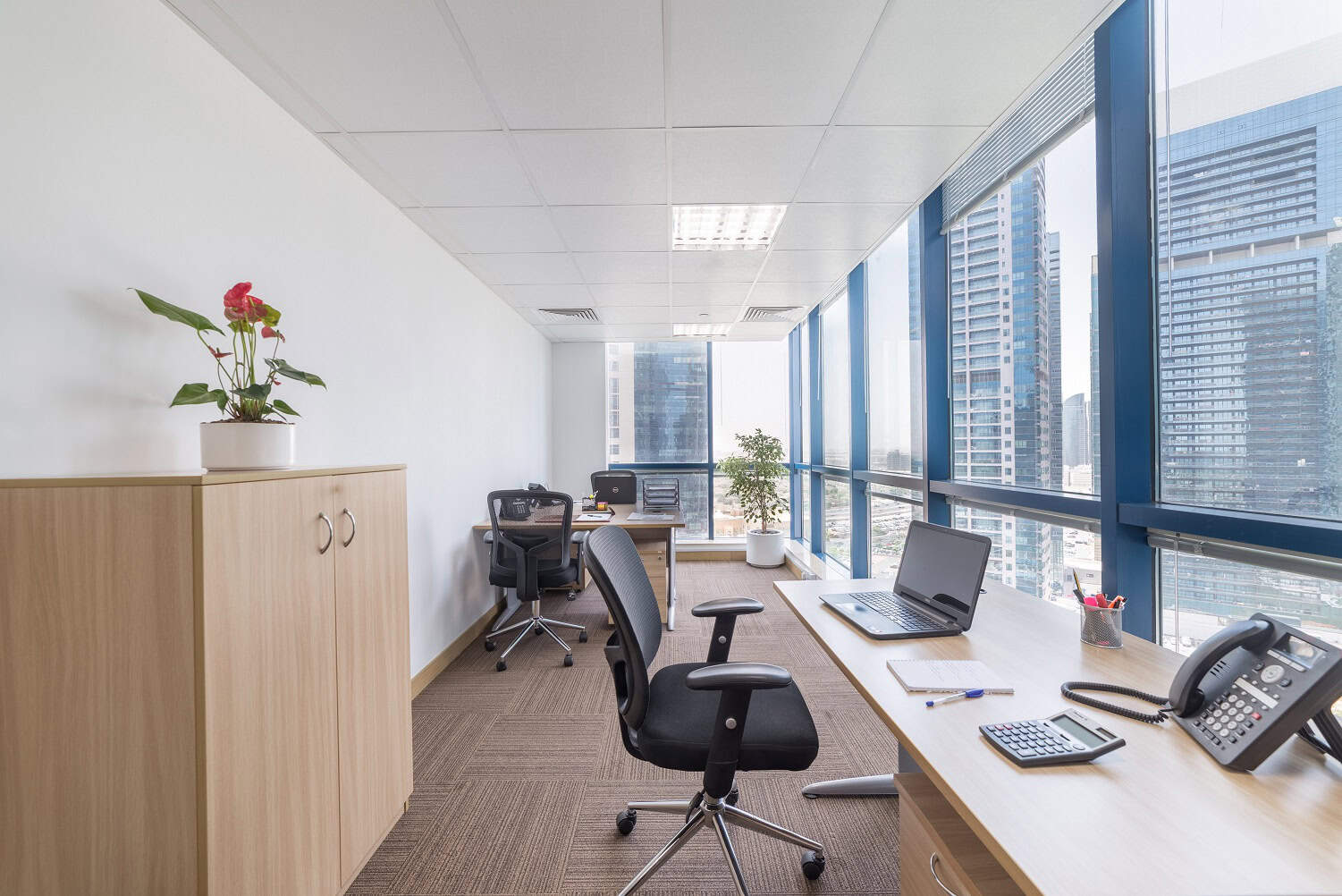 Modern office with large windows and coworking desks in Dubai, UAE, promoting productivity and business growth.