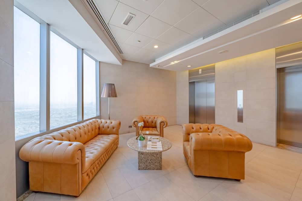 Luxurious lounge area with plush tan sofas and natural light in a Nextspace UAE office.