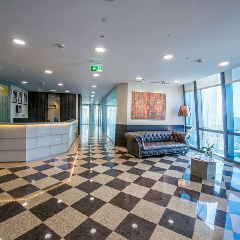 Bright, stylish office reception area with large windows overlooking Dubai skyline and check-in desk.