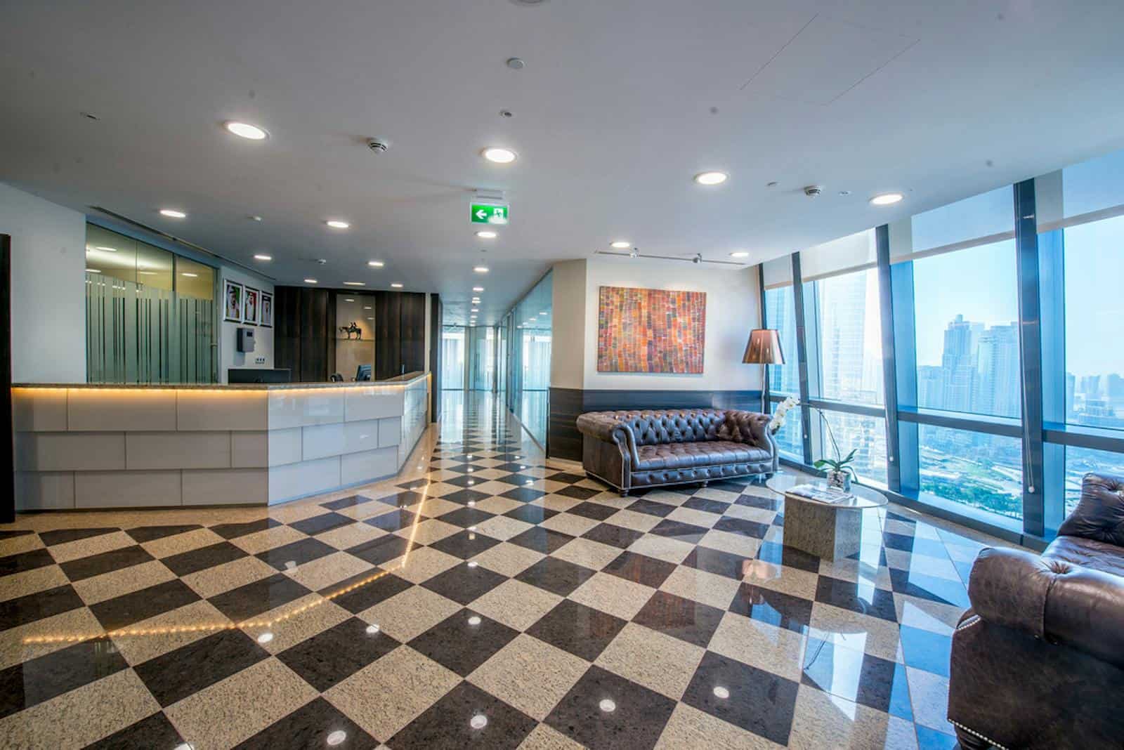 Bright, stylish office reception area with large windows overlooking Dubai skyline and check-in desk.