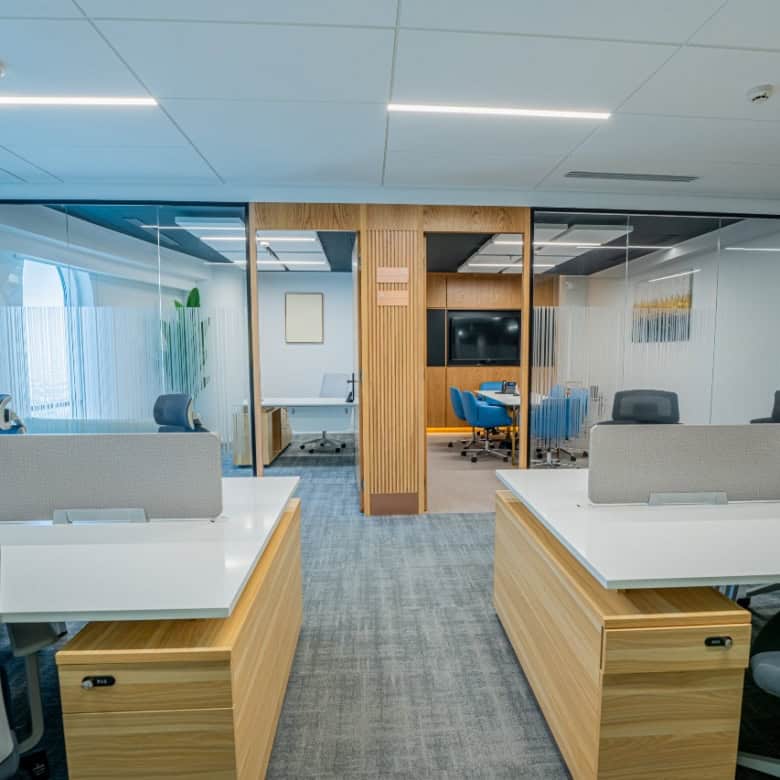 Contemporary work environment with private meeting rooms, ergonomic chairs, and glass partitions.