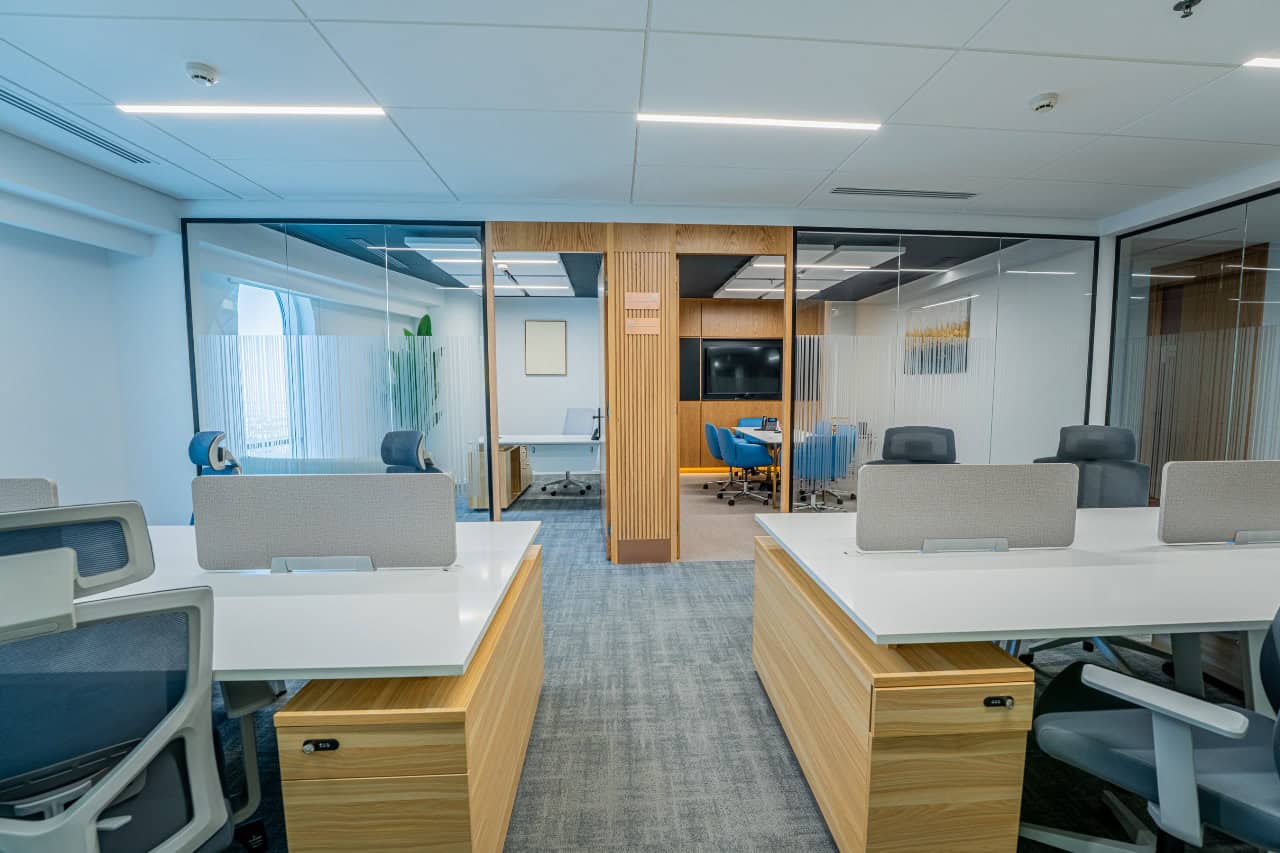 Contemporary work environment with private meeting rooms, ergonomic chairs, and glass partitions.