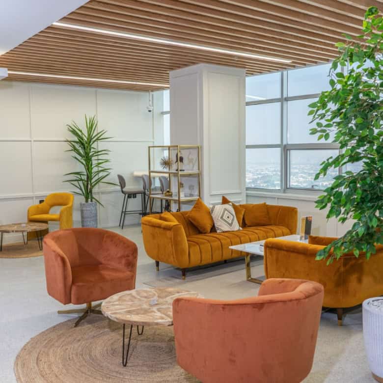 Beautiful stylish office lounge with vibrant seating, indoor plants, and large windows in Dubai.