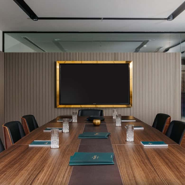 Modern corporate meeting room at Nextspace UAE featuring a large conference table, black chairs, and a digital screen for seamless business meetings.