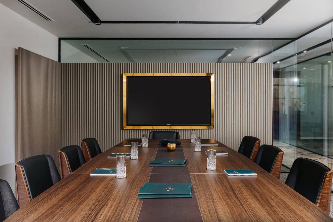 Modern corporate meeting room at Nextspace UAE featuring a large conference table, black chairs, and a digital screen for seamless business meetings.