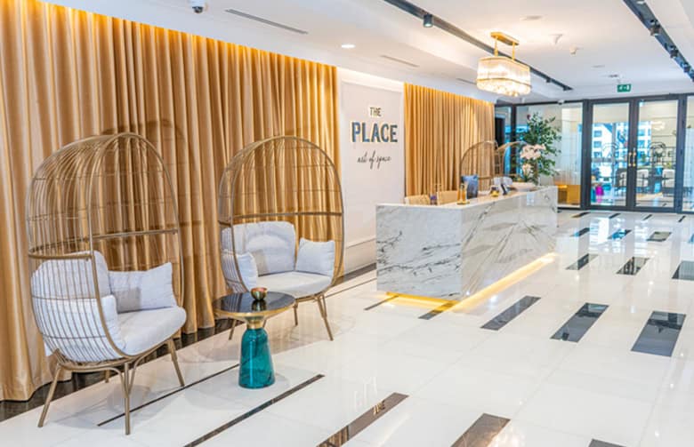 Elegant coworking lobby with comfortable chairs, marble counter, and warm lighting in Dubai UAE.