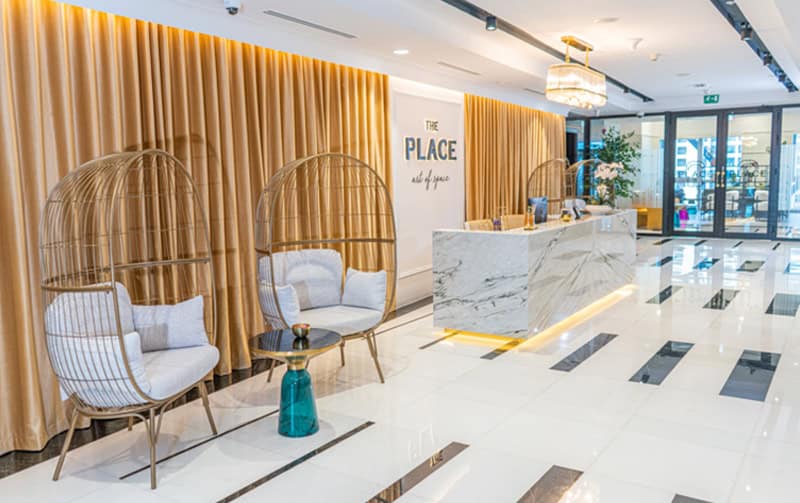 Elegant coworking lobby with comfortable chairs, marble counter, and warm lighting in Dubai UAE.