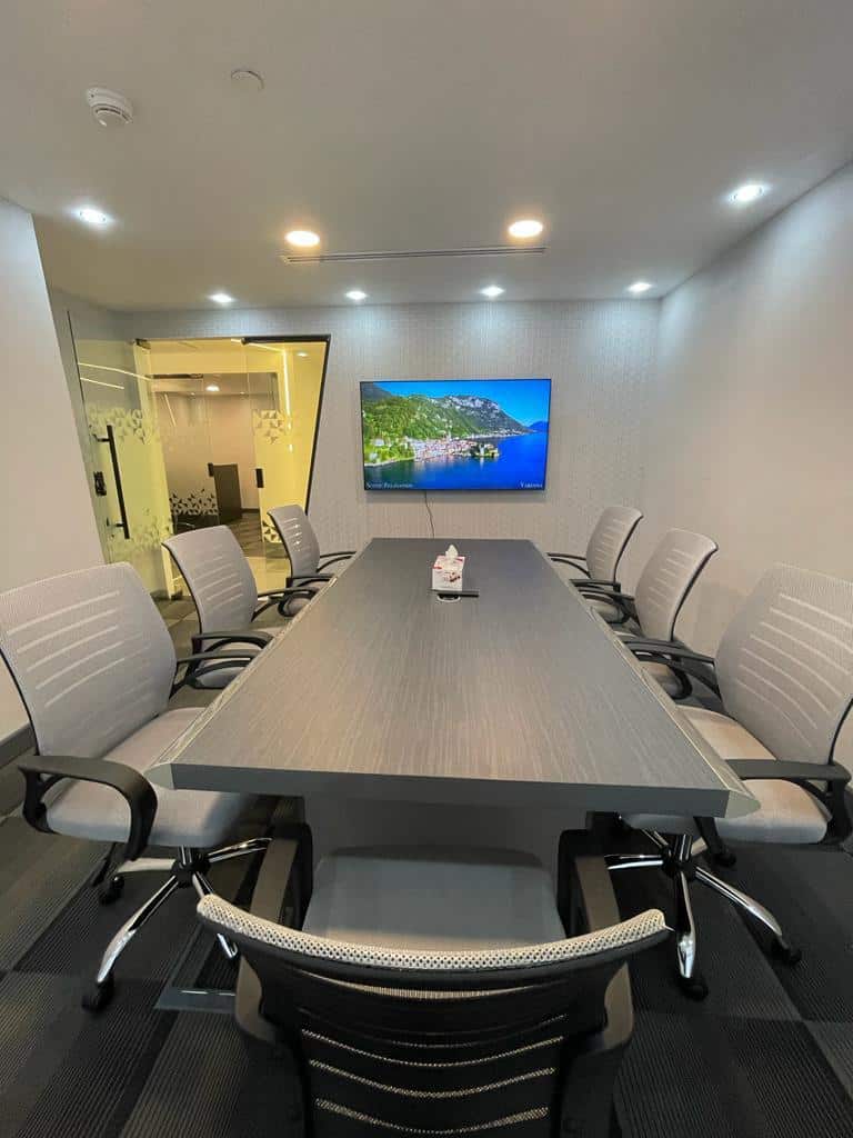 UAE business meeting room with conference table, chairs, and wall-mounted TV.