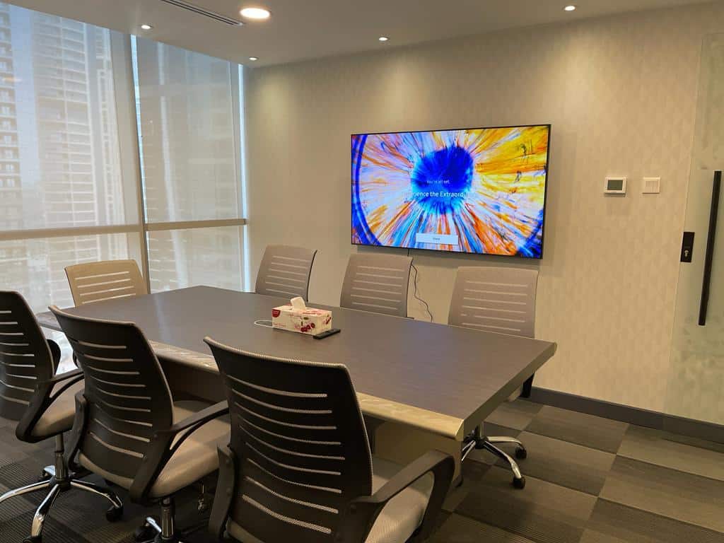 High-quality image of a contemporary conference room at Nextspace UAE with a digital screen and ergonomic chairs.