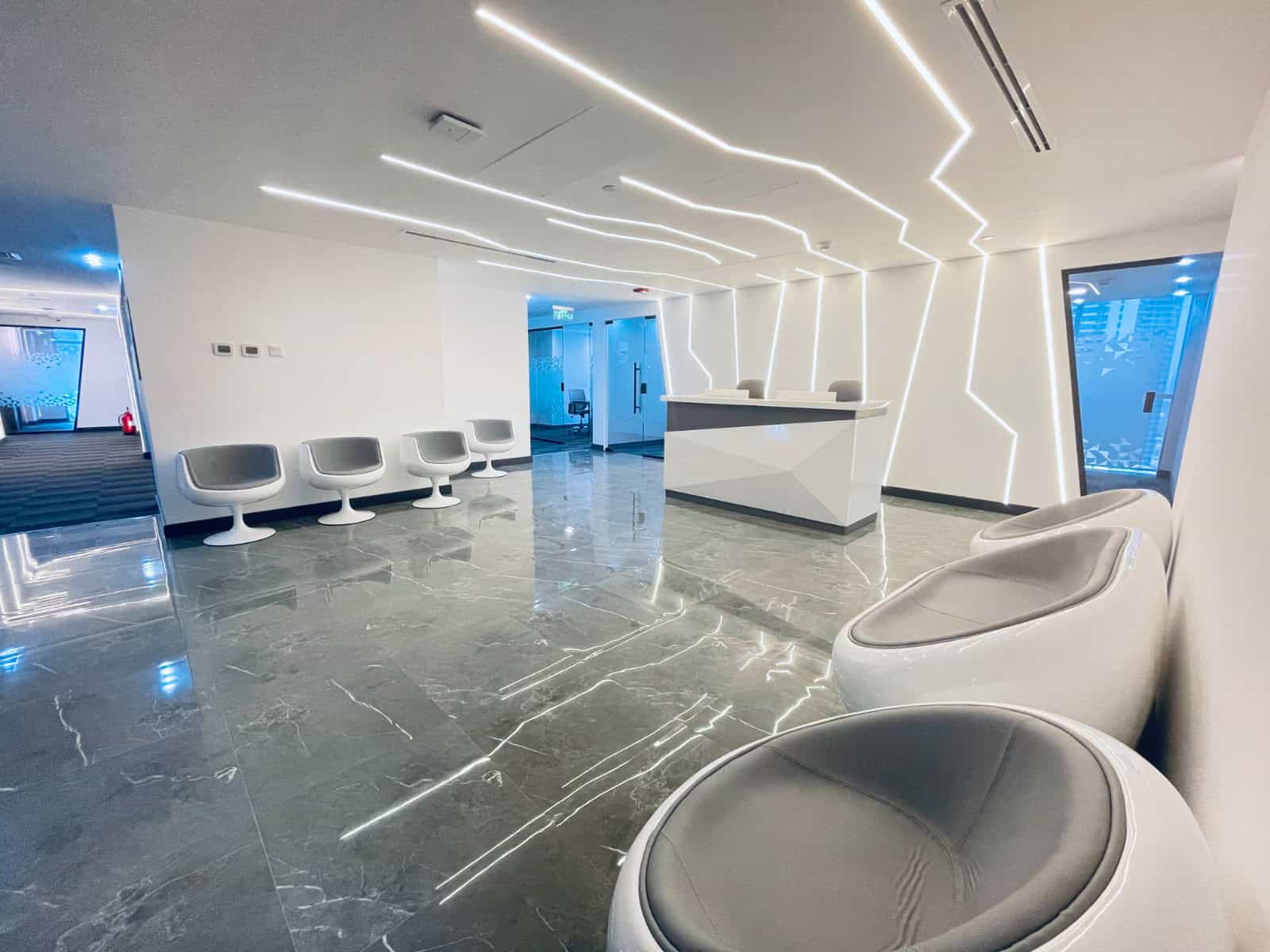 Luxury office reception area with sleek white seating and innovative lighting design.