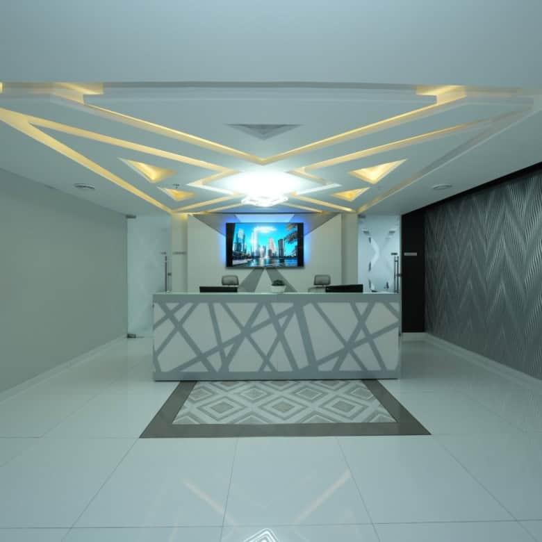 Stylish UAE coworking space reception with contemporary decor and digital display screen.